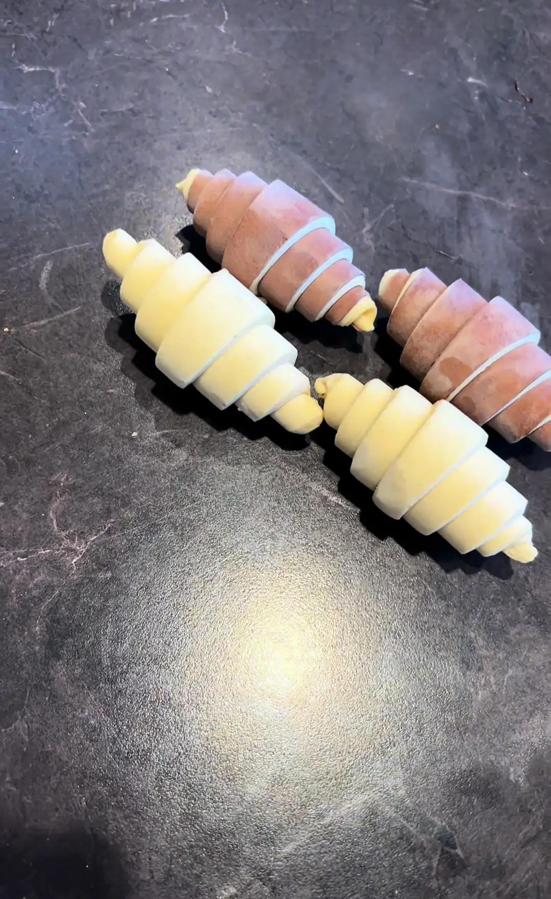 Croissants crus façonnés à la main, posés sur un plan de travail sombre